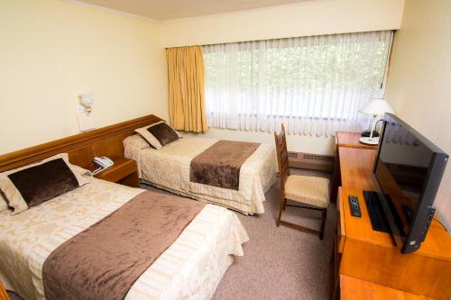 Habitación de hotel con 2 camas y TV de pantalla plana. en Villa del Rio Express en Valdivia