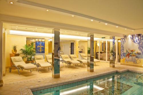 a hotel lobby with a swimming pool and chairs at Chateau Fontenay in Bad Wörishofen