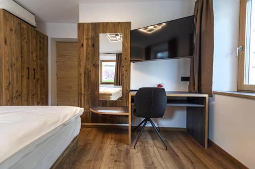 a bedroom with a bed and a desk and a chair at Apartment Fina in Ortisei