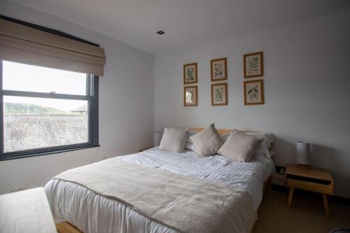 a bedroom with a white bed with a window at 4 Bedroom Cottage with panoramic Harbour views in Falmouth