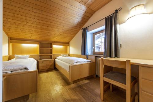 een slaapkamer met twee bedden, een bureau en een raam bij Panorama Apartment Pizaut in Ortisei