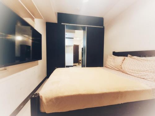 ein kleines Schlafzimmer mit einem Bett und einem TV in der Unterkunft SweetSuites at Pine Crest #T3-1212 in Manila