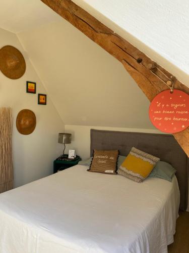 a bedroom with a bed with white sheets and wooden beams at La Métairie in Domloup