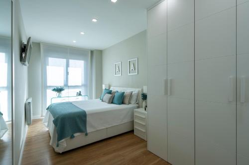 Dormitorio blanco con cama y pared de cristal en GUNI SUITES JARDINEs, en Granada