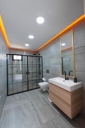 een badkamer met een wastafel, een toilet en een spiegel bij Antalya La Serenite Villa in Yukarıkaraman