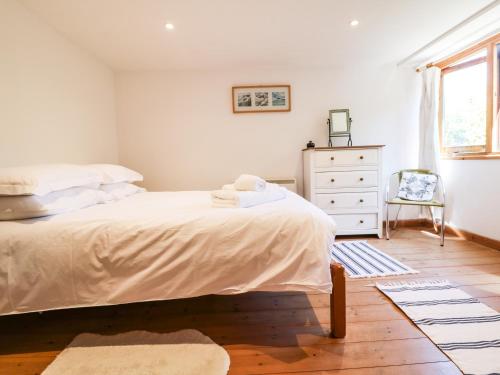 a bedroom with a bed and a dresser and a window at Lower Rissick Cottage in Penzance