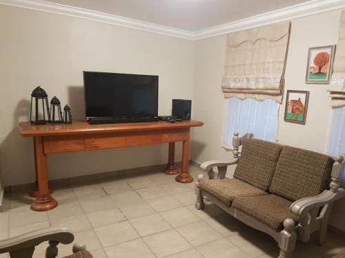 sala de estar con TV, mesa y silla en Genie's Nest Ooie 3, en Pretoria