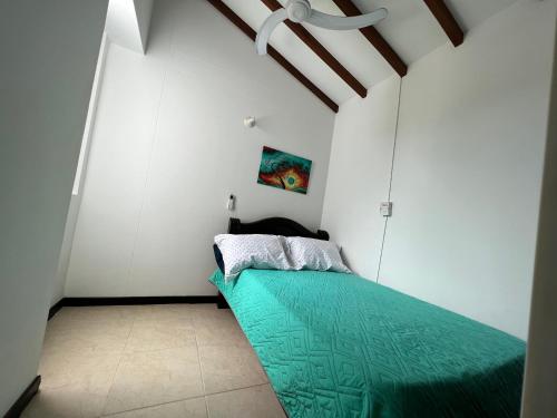 a bedroom with a green bed in a white room at Hermoso apartasol en santafe de Antioquia. in Santa Fe de Antioquia