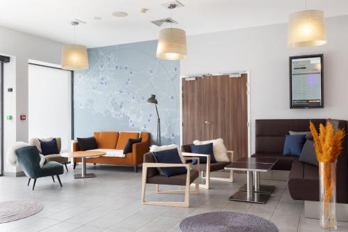 a lobby with couches and chairs and a map on the wall at Holiday Inn Express - Marseille Airport by IHG in Vitrolles