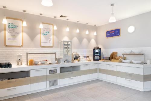 a large kitchen with white cabinets and appliances at Holiday Inn Express - Marseille Airport by IHG in Vitrolles
