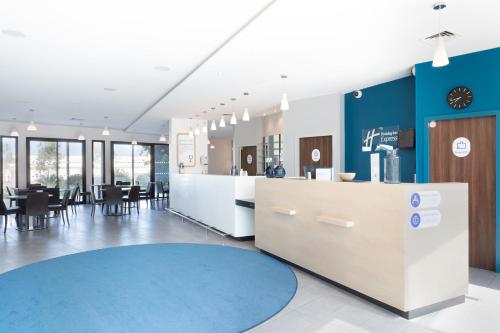 a lobby with a restaurant with tables and chairs at Holiday Inn Express - Marseille Airport by IHG in Vitrolles