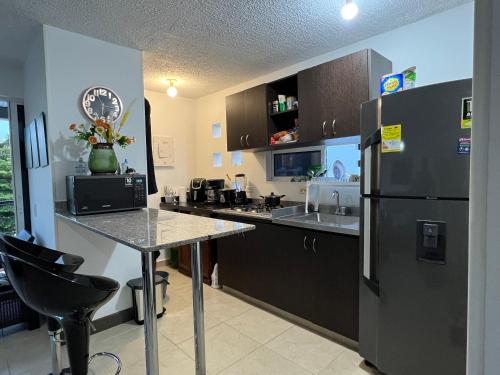 a kitchen with a black refrigerator and a table at Hermoso apartasol en santafe de Antioquia. in Santa Fe de Antioquia