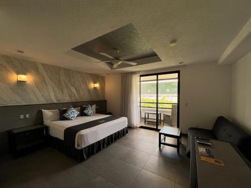 1 dormitorio con 1 cama grande y balcón en Aspira Hotel Playa del Carmen, en Playa del Carmen