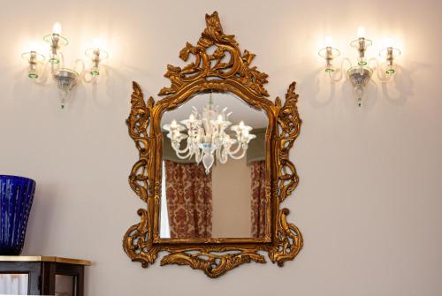 an ornate gold mirror hanging on a wall with lights at Hotel Villa Edera in Venice-Lido