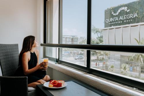 uma mulher sentada numa mesa a olhar pela janela com uma bebida em Aspira Hotel Playa del Carmen em Playa del Carmen