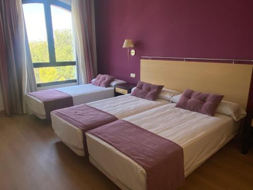 duas camas num quarto de hotel com paredes roxas em Hotel Equo Aranjuez em Aranjuez