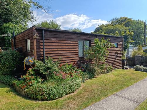 a small wooden cabin in a yard with plants at Rivermead Holidays in Saint Breward