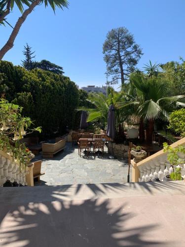 a patio with tables and umbrellas and trees at Hotel Alexandra - Boutique Hotel in Juan-les-Pins