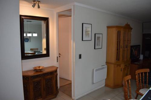 een woonkamer met een spiegel en een houten kast bij VIVE LA EXPERIENCIA, PLAYA, SPA, CASINO DE JUEGOS in Coquimbo