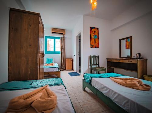 a bedroom with two beds and a desk and a sink at Bamboo House Hotel Dahab in Dahab