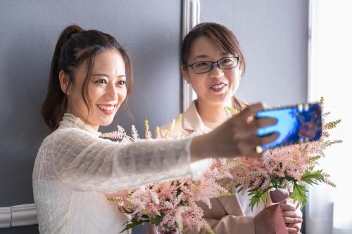 a woman taking a picture of a bride holding flowers at Hotel Teiregikan in Tobe