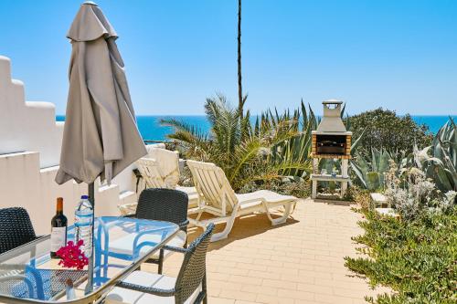a patio with chairs and an umbrella and a grill at Apartment Centeanes in Carvoeiro