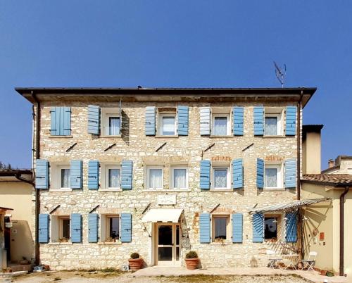 un viejo edificio de piedra con persianas azules. en La Fassina, en Valdobbiadene