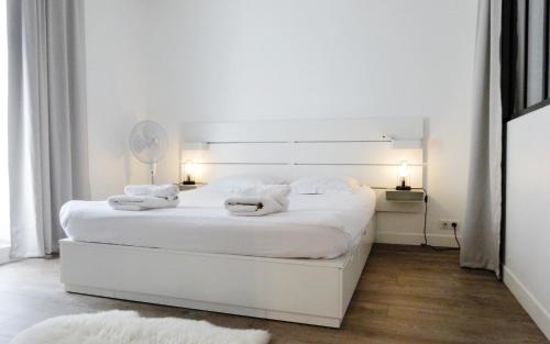 biała sypialnia z białym łóżkiem z białą pościelą w obiekcie Elégant appartement dans le quartier Concorde à Paris w Paryżu
