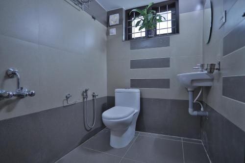 a bathroom with a toilet and a sink and a window at God's gift in Devikolam