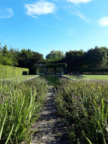 a path through a garden with a house in the background at Domein Den Buiten Bed And Breakfast DnD in Sint-Niklaas