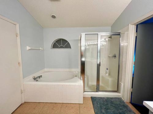 y baño blanco con bañera y ducha. en Tampa Getaway Pool House, en Tampa