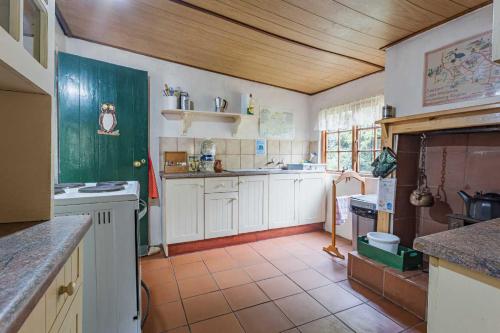uma cozinha com armários brancos e piso em azulejo em Back o' the Moon Holiday cottage em Hogsback
