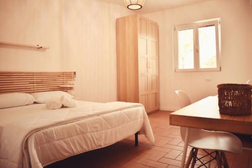 a bedroom with a bed and a table and a window at Il Casale dei Calanchi in Aliano