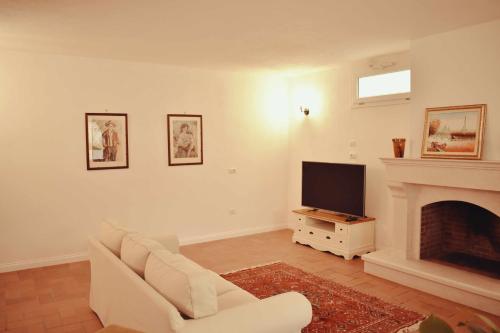 een woonkamer met een witte bank en een televisie bij Il Casale dei Calanchi in Aliano