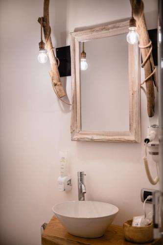 a bathroom with a white bowl sink and a mirror at Love & Fama Hotel in Sabaudia