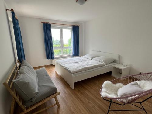 ein Schlafzimmer mit einem Bett, einem Stuhl und einem Fenster in der Unterkunft Ferienwohnung Strandsegler, Ferienanlage "Blaumuschel" in Lubmin