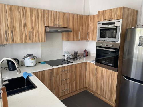 La cuisine est équipée d'armoires en bois et d'un réfrigérateur en acier inoxydable. dans l'établissement BEACH VILLA ROCCA, à Grand Gaube