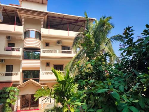 a tall building with trees in front of it at The Narrow Way Edward Guest House in Candolim