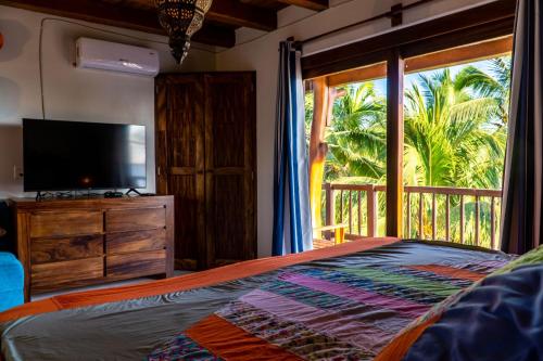 a bedroom with a bed and a tv and a window at Hotel Bajito Bay in Troncones