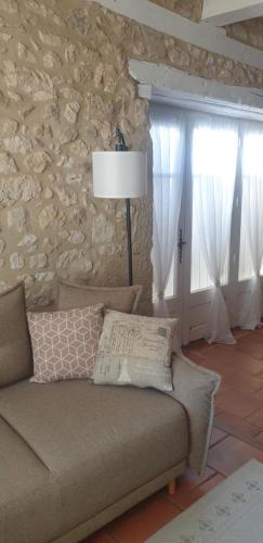 a living room with a couch and a stone wall at Gîte du Tilleul 6 pers - Au Clos de Parranquet in Parranquet