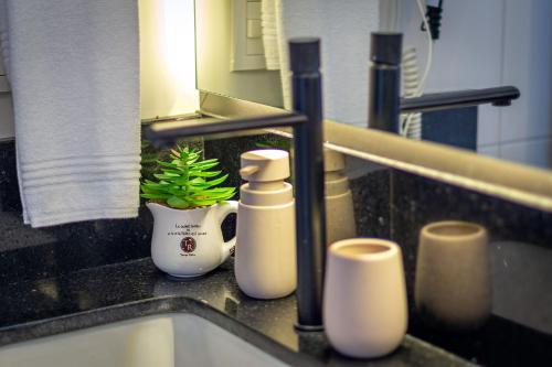 a bathroom sink with a faucet and a plant at Casa Quinta do Palácio - Stay House Temporada in Canela