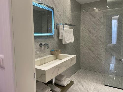 een badkamer met een wastafel, een spiegel en een douche bij HOTEL UJVARA in Belsh-Qendra