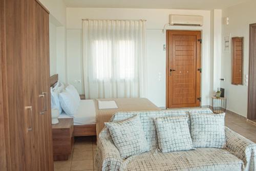 a bedroom with a bed and a couch and a window at Apartment by the sea in Stalida