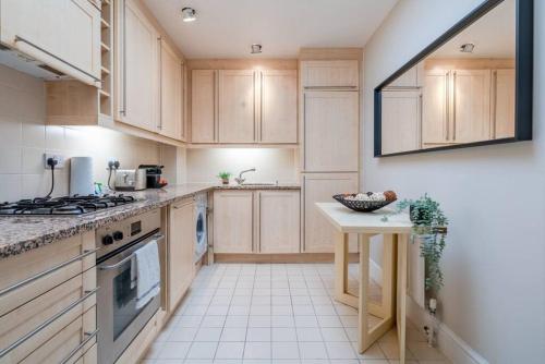 a kitchen with wooden cabinets and a table in it at Be London - Marylebone Residences in London