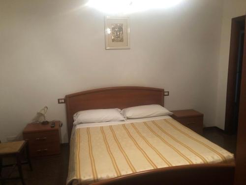 Dormitorio pequeño con cama con cabecero de madera en Le camere di aisa, en Santa Maria degli Angeli
