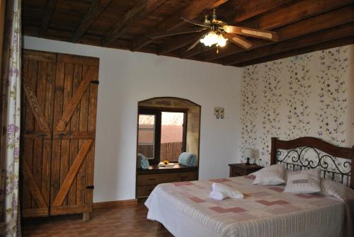 Casa Rural Aca y Papá Juan في غيمار: غرفة نوم بسرير مع مروحة سقف وباب