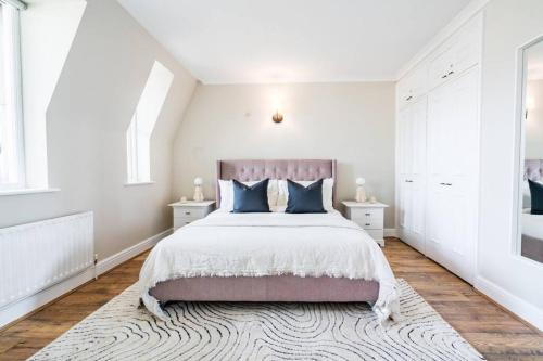 a white bedroom with a large bed with blue pillows at Be London - Marylebone Residences in London