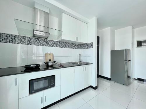 een witte keuken met een spoelbak en een koelkast bij PTH Residence in Phnom Penh
