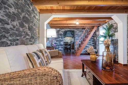 a living room with a white couch and a stone wall at Rainbow Cottage by Madeira Sun Travel in Ponta do Pargo