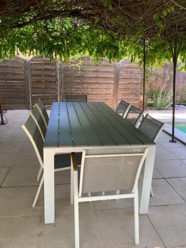 a picnic table with four chairs around it at Le clos des olivettes in Sainte-Croix-de-Quintillargues